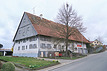Gebäude von Südosten mit Blick auf vordere, östliche Längs- und vordere, südliche Schmalseite, links mit Sockelgeschoss, rechts mit Geländeanhebung für die frühere Hocheinfahrt / Bauernhaus in 78655 Dunningen (2023 - Stefan King, Freiburg)